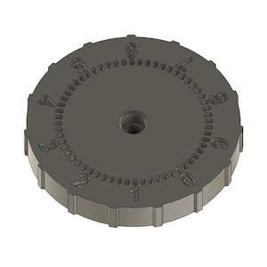 May include: A dark gray, circular dial with the numbers 0 through 9 etched around the perimeter. The dial has a central hole and a ridged edge. The numbers are evenly spaced and clearly visible against the gray background.
