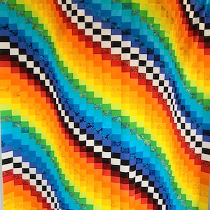 May include: A colourful quilt with a rainbow pattern and a black and white chequered design. The quilt is made of squares of fabric sewn together.