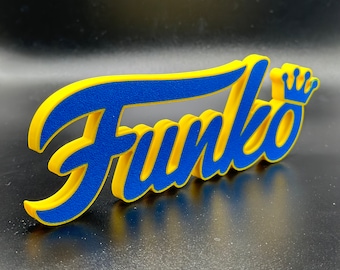 May include: A blue and yellow Funko logo with a crown on top. The logo is made of a textured material and is three-dimensional.
