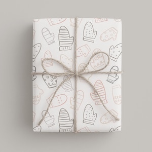 May include: A wrapped gift with a white background featuring a pattern of mittens in gray and pink. The gift is tied with twine in a bow. The mittens have various designs, including stripes and polka dots, creating a festive winter theme.