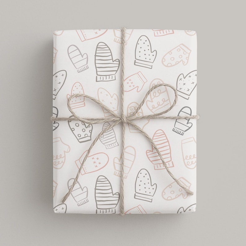 May include: A wrapped gift with a white background featuring a pattern of mittens in gray and pink. The gift is tied with twine in a bow. The mittens have various designs, including stripes and polka dots, creating a festive winter theme.