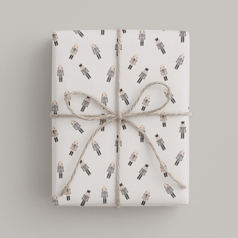 May include: A wrapped gift with white paper featuring a repeating pattern of watercolor-style figures in gray, black, and tan. The gift is tied with twine in a bow.
