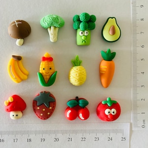 May include: A selection of miniature food-themed figurines. The set includes a mushroom, broccoli, avocado, banana, corn, pineapple, carrot, strawberry, cherries, and a tomato. Each piece is brightly coloured and detailed.