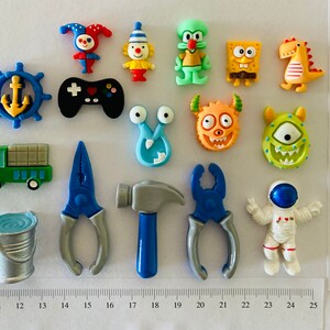May include: A selection of small, colourful figurines and tools. Includes a jester, clown, Squidward, SpongeBob, a dinosaur, a truck, a bucket, a controller, a hammer, pliers, an astronaut, and more. The items are arranged on a white surface.