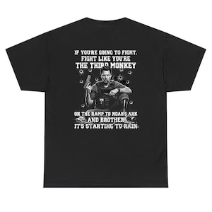 May include: Black t-shirt with a graphic of a man holding a gun, surrounded by bullet holes. Text on the shirt reads "IF YOU'RE GOING TO FIGHT. FIGHT LIKE YOU'RE THE THIRD MONKEY. ON THE RAMP TO NOAH'S ARK AND BROTHER IT'S STARTING TO RAIN."