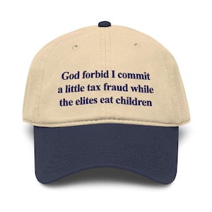 Può includere: Un cappellino da baseball beige con visiera blu scuro e un bottone blu scuro sulla parte superiore. La parte anteriore del cappellino presenta il testo ricamato: God forbid I commit a little tax fraud while the elites eat children, in un carattere serif blu scuro.