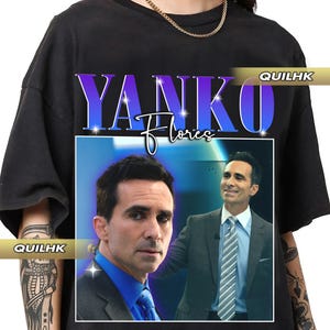 May include: Black t-shirt featuring a graphic of a man in a suit with the name "YANKO" in a gradient purple font above the name "Flores" in a cursive font. The shirt has the text "QUILHK" on the side.