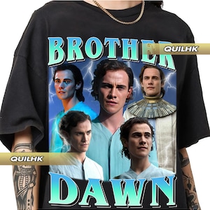 Puede incluir: Camiseta negra con un gráfico que dice "BROTHER DAWN" en verde azulado y blanco. El gráfico presenta imágenes de varias personas sobre un fondo de rayos. También es visible la marca "QUILHK".