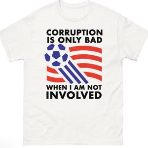 May include: A white short-sleeve t-shirt featuring a graphic of a blue football with motion lines over red and white horizontal stripes. The text reads: CORRUPTION IS ONLY BAD WHEN I AM NOT INVOLVED, printed in bold black capital letters.