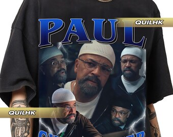 May include: Black t-shirt featuring a graphic design with the name "PAUL CHRISTOPHER" in a vintage style. The design includes multiple images of a man wearing glasses and a white cap, with lightning bolt accents.