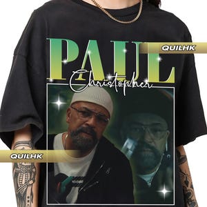 May include: Black t-shirt featuring a graphic of a man wearing glasses and a beanie. The text "PAUL Christopher" is printed in a gradient green and yellow font. The brand name "QUILHK" is printed on the shirt.