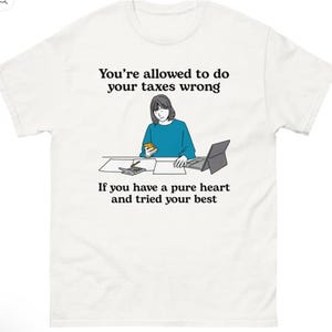 May include: White t-shirt with a graphic illustration and text. The illustration depicts a person at a desk with a calculator and laptop. The text reads, "You're allowed to do your taxes wrong. If you have a pure heart and tried your best."
