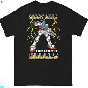 May include: Black t-shirt with a graphic of a robot holding a laser sword, with the text "SORRY GIRLS I ONLY HANG WITH MODELS" in yellow and white. The robot is white, red, blue, and yellow, with yellow lightning bolts in the background.