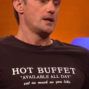 May include: A black t-shirt with the words "HOT BUFFET" in large white capital letters. Below, in smaller white text, it reads "AVAILABLE ALL DAY" and "eat as much as you like".
