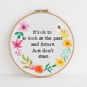 May include: Embroidered hoop art featuring a floral wreath and the quote "It's ok to look at the past and future. Just don't stare."