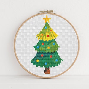 May include: A green and yellow Christmas tree with a yellow star on top and colorful ornaments. The tree is in a wooden embroidery hoop.