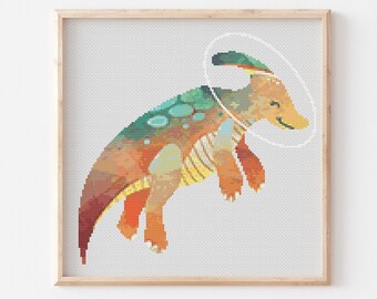 May include: A cross-stitch pattern featuring a colorful, cartoon-style dinosaur with a halo. The dinosaur is orange, yellow, green, and brown. The halo is white.