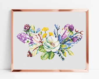 Könnte beinhalten: Ein Kreuzstichmuster mit einem bunten Blumenstrauß mit violetten, blauen, weißen, gelben und grünen Blumen. Der Strauß ist in einem kupferfarbenen Rahmen gerahmt.