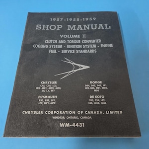 May include: A vintage shop manual, Volume II, for Chrysler, Dodge, Plymouth, and De Soto vehicles from 1957-1959. The cover is dark grey with white text, listing topics like clutch, cooling, and fuel systems. The Chrysler Corporation of Canada, Limited logo is visible.
