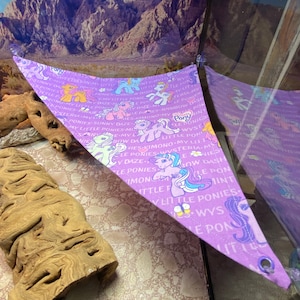 May include: A purple triangle-shaped fabric hammock with a My Little Pony theme. The hammock features a variety of My Little Pony characters and the words "My Little Ponies" repeated throughout.