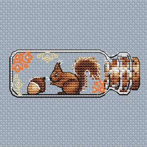 Peut inclure: Un écureuil brun avec une queue touffue est à l'intérieur d'un bocal en verre transparent avec un couvercle en liège. L'écureuil tient une noix brune dans ses pattes. Le bocal a un motif décoratif sur le côté.