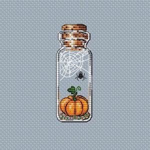 May include: A glass jar with a cork lid contains a small orange pumpkin and a black spider web with a black spider.