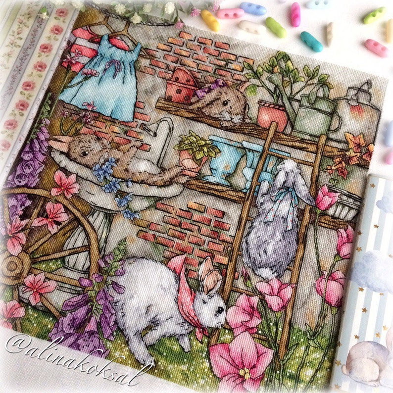May include: A detailed illustration depicts a whimsical garden scene with rabbits. A white rabbit with a pink scarf is surrounded by pink flowers. Other rabbits are on shelves with plants and a blue dress hangs on a clothesline. The artwork has a vintage, storybook feel.