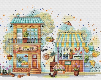 May include: A cross-stitch illustration of a flower shop with a brown brick facade and a sign that reads "FLOWER".  A smaller shop with a striped awning is next door, selling plants and flowers.  The shops are surrounded by a blue and orange watercolor background.