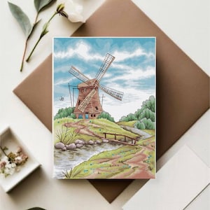 Puede incluir: Un paisaje de punto de cruz representa un molino de viento en una colina, con un camino que conduce a un pequeño puente sobre un arroyo. El cielo es azul con nubes blancas. El molino es marrón y el paisaje es verde y beige.