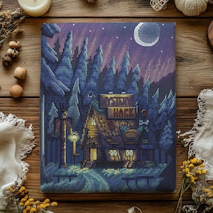 Pode incluir: Arte em ponto cruz com uma cena noturna de floresta com uma cabana. A cabana tem o texto "Mystery Shack" em um letreiro. A obra de arte é em tons de azul, verde e roxo, com uma lua crescente no céu.