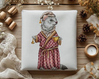 Puede incluir: Un bordado de punto de cruz sobre tela blanca que muestra un hurón gris con un gorro de dormir beige y una bata de color rojo oscuro con estampado y cuello dorado. El hurón sostiene una pequeña campana dorada y una taza de té dorada.