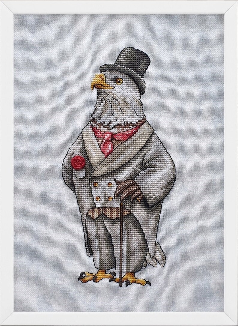 May include: A cross-stitch embroidery of an eagle dressed in a formal gray suit, a red necktie, and a black top hat. The eagle holds a walking cane and features a red rose on its lapel. The artwork is framed in a simple white border.