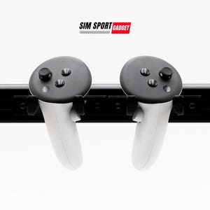 May include: Two white VR controllers with black buttons are mounted on a black rail. The controllers are hanging from the rail. The text "SIM SPORT GADGET" is printed above the rail.