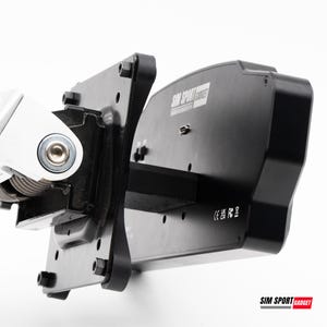 Puede incluir: Primer plano de un componente negro y plateado de simulador de carreras. El componente tiene forma rectangular con el texto "SIM SPORT GADGET" impreso. El componente está montado sobre una superficie blanca.
