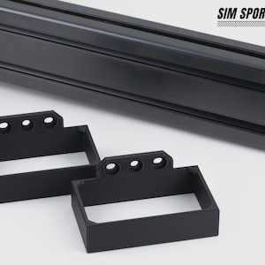 Puede incluir: Soportes rectangulares negros con tres agujeros y una barra de metal negra. Los soportes están diseñados para sujetar algo en su lugar. El logotipo "SIM SPORT GADGET" está en la esquina superior derecha.
