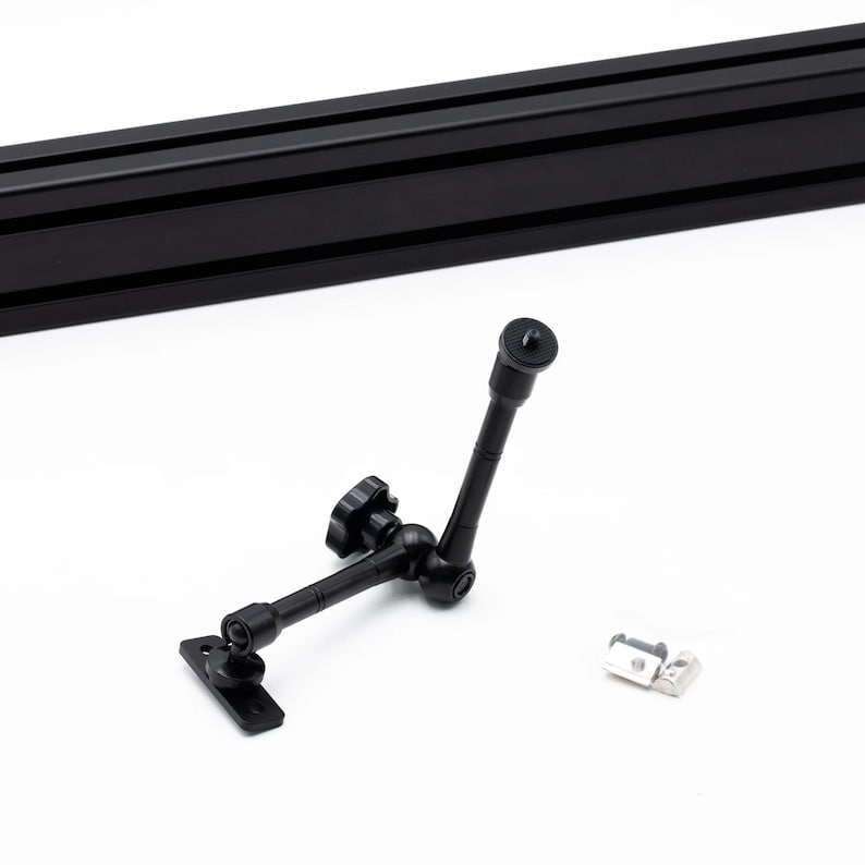 May include: Black adjustable camera arm with a ball joint and a 1/4-inch screw mount. The arm is attached to a black metal plate. A silver metal bracket is also included.
