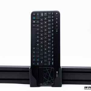 Puede incluir: Teclado inal&aacute;mbrico negro con panel t&aacute;ctil integrado. El teclado tiene un dise&ntilde;o QWERTY completo con teclas de acento azul. Est&aacute; montado en un soporte negro. El logotipo de Logitech es visible en la esquina inferior derecha.