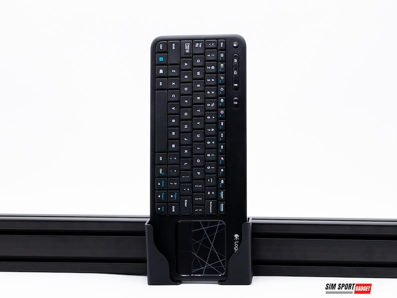 Puede incluir: Teclado inal&aacute;mbrico negro con panel t&aacute;ctil integrado. El teclado tiene un dise&ntilde;o QWERTY completo con teclas de acento azul. Est&aacute; montado en un soporte negro. El logotipo de Logitech es visible en la esquina inferior derecha.