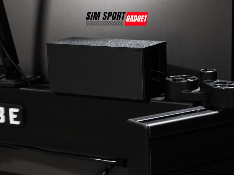 Pode incluir: Uma caixa preta com o texto "SIM SPORT GADGET" em letras vermelhas no topo. A caixa est&aacute; sobre uma superf&iacute;cie preta.