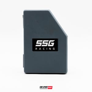 Op de afbeelding: Een donkergrijze, rechthoekige elektronische behuizing met een schuine bovenhoek. De voorzijde is voorzien van een zwart rechthoekig label met de witte tekst SSG RACING in een vet, modern lettertype. De behuizing heeft een matte afwerking.