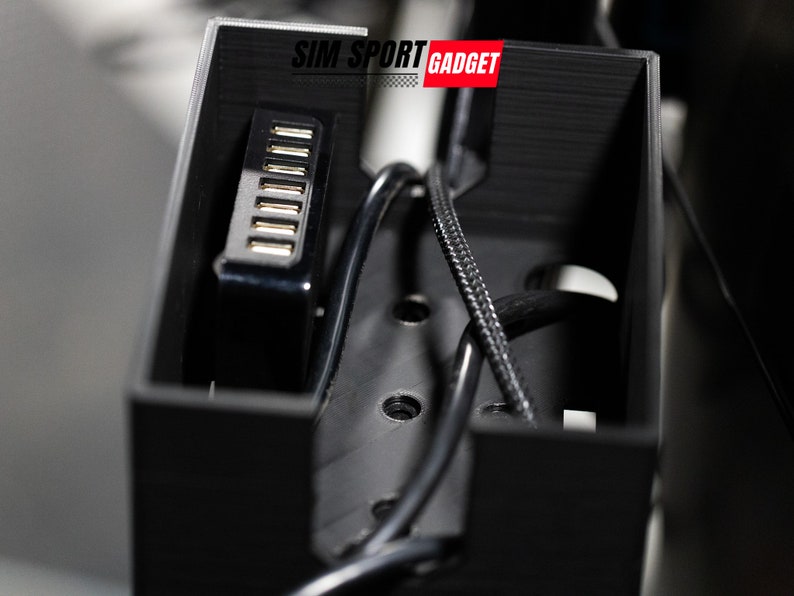 Pode incluir: Uma caixa de pl&aacute;stico preta com um hub USB no interior. A caixa tem o texto "SIM SPORT GADGET" impresso na parte superior.