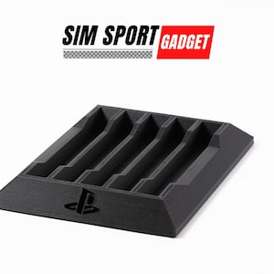 May include: Black plastic game controller stand with multiple slots. The stand has a PlayStation logo and the text "SIM SPORT GADGET" in white and red.