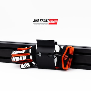 May include: A black metal glove holder with a pair of orange and white racing gloves hanging on it. The holder is attached to a black metal track system. The text "SIM SPORT GADGET" is visible above the holder.