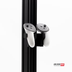 May include: A black metal stand with two white VR controllers mounted on it. The stand has a black and red logo that says "SIM SPORT GADGET".