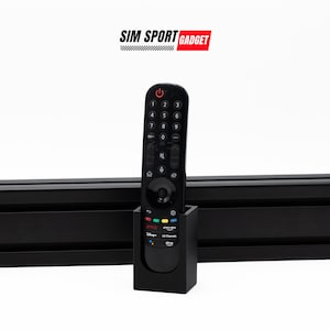 Può includere: Porta telecomando nero con un telecomando nero all'interno. Il supporto ha un'etichetta che dice "Netflix, Prime Video, Disney+, LG Channels, Sling".