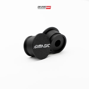 May include: Two black cylindrical objects with a central hole and a textured surface. The text "SIMAGIC" is printed in white on one of the objects. The objects are set against a white background.