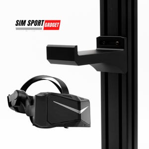 May include: A black VR headset with a silver accent on the front, hanging from a black metal bracket attached to a black metal pole. The bracket is labeled "SIM SPORT GADGET".