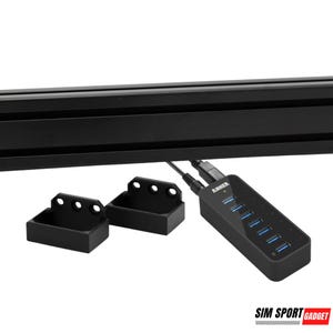 May include: A black USB hub with the Anker logo and seven blue USB ports. The hub is connected to a black cable and is sitting on a black surface. Two black plastic brackets are also visible in the image.