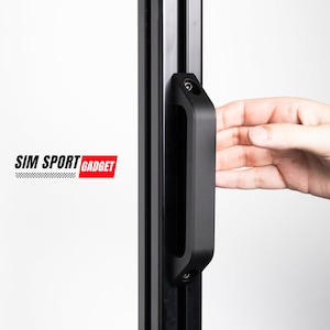 May include: Black metal door handle with a recessed grip. The handle is attached to a black metal frame. The text "SIM SPORT GADGET" is visible in the background.