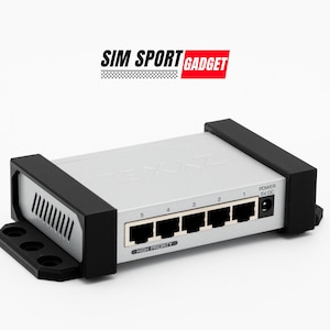以下が含まれることがあります： 5つのイーサネットポートと「POWER 5V DC」と表示された電源ポートを備えたシルバーのネットワークスイッチ。スイッチは、エッジに黒いプラスチック製のケーシングが付いています。